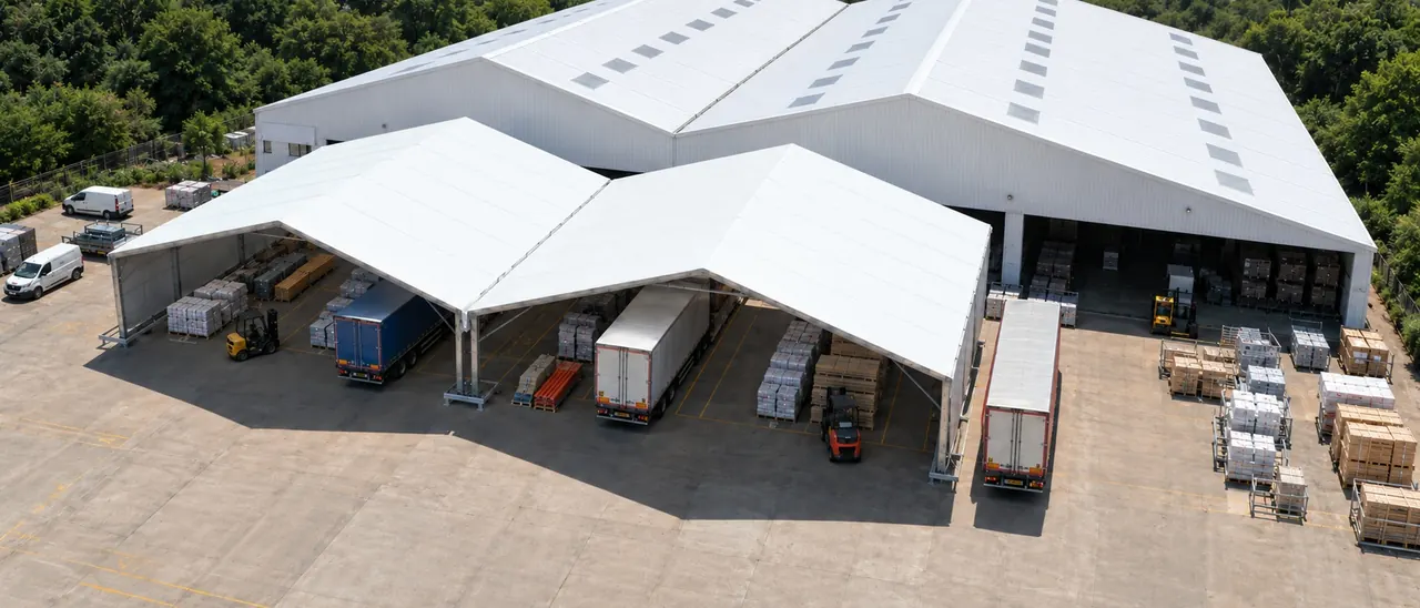 Aerial view of a white industrial canopy covering a loading yard, lorries backed up beneath it