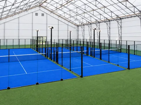 Indoor padel courts side by side beneath a clear span roof