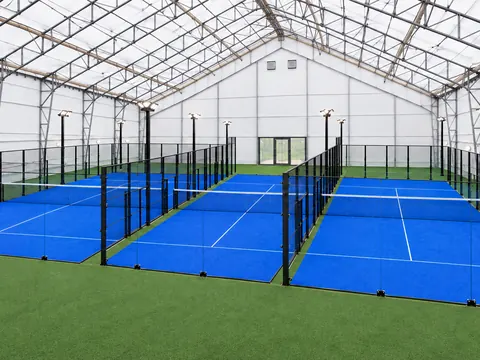 Indoor padel courts with lighting columns set outside the playing area