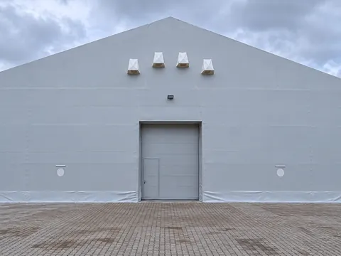 The gable end of a PVC clad temporary building with vents above the door
